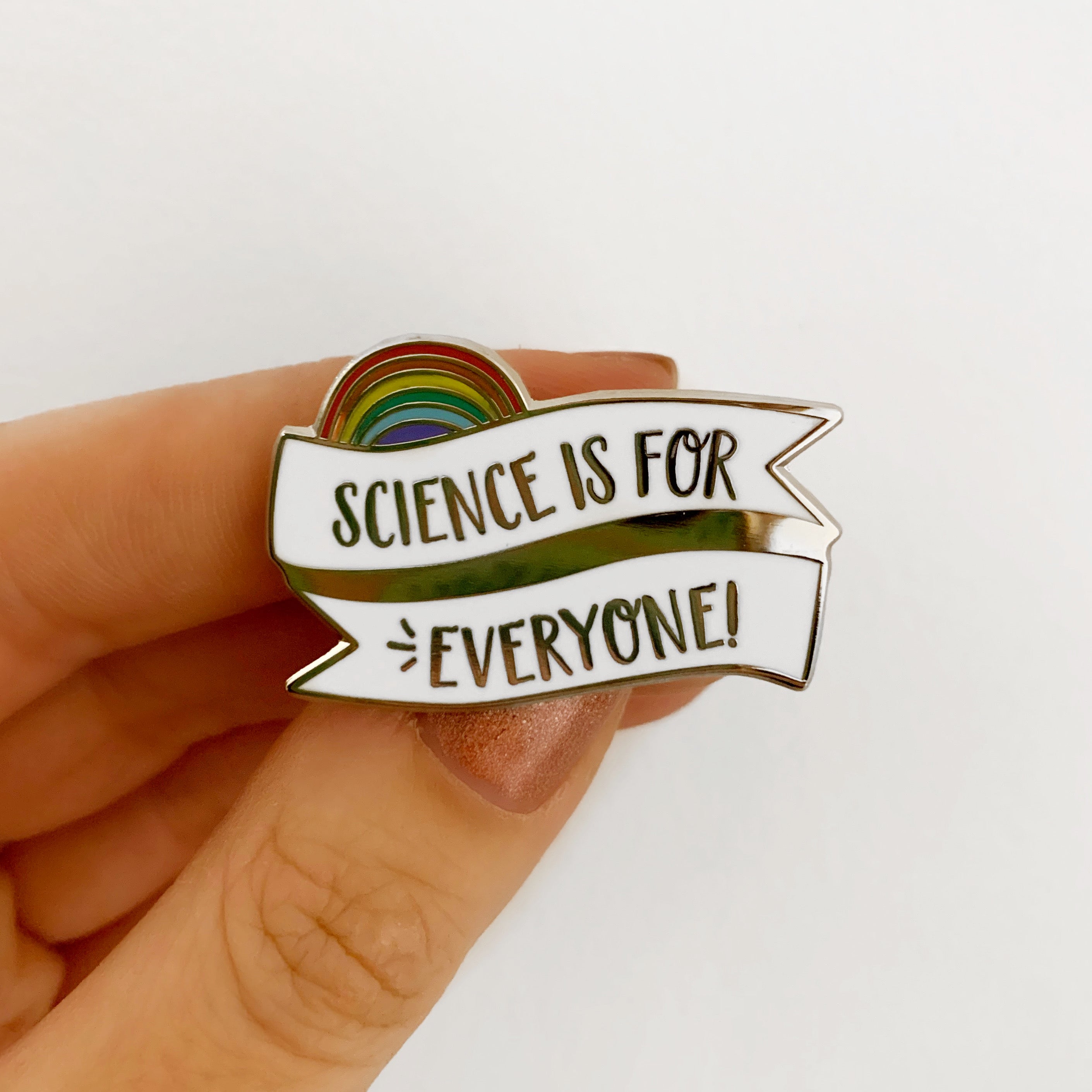 Pin with 'Science is for Everyone!' text held by a hand on a white background