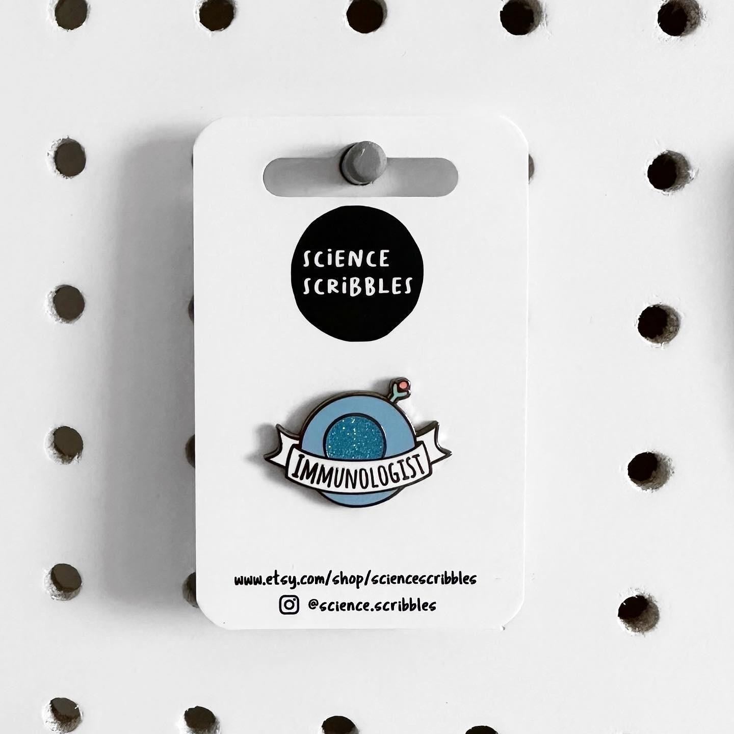 Enamel pin on a card with 'Science Scribbles' branding, displayed on a polka dot background.