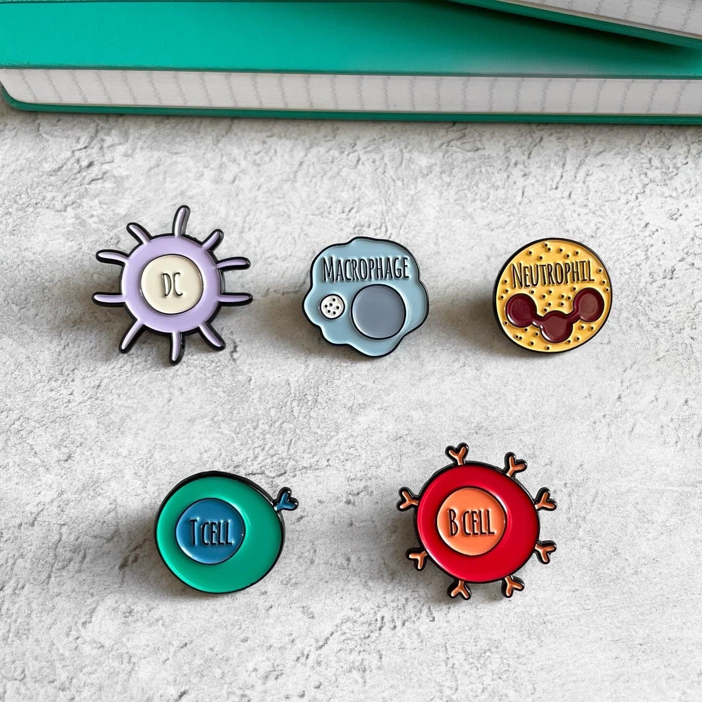 Five colorful pins with different designs on a textured surface.