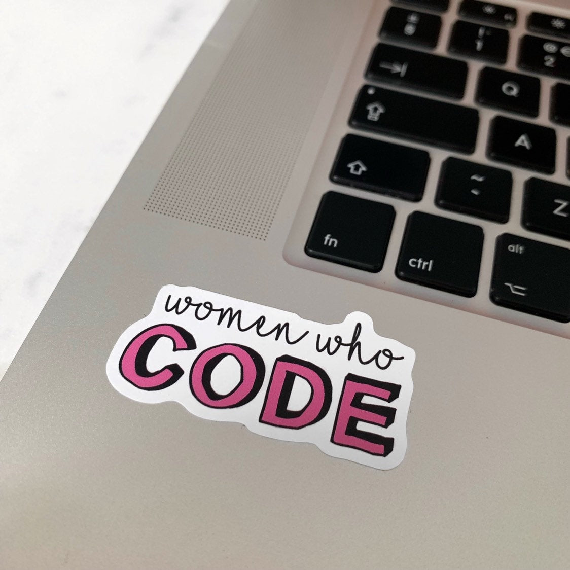 Laptop with a 'women who code' sticker on the palm rest area