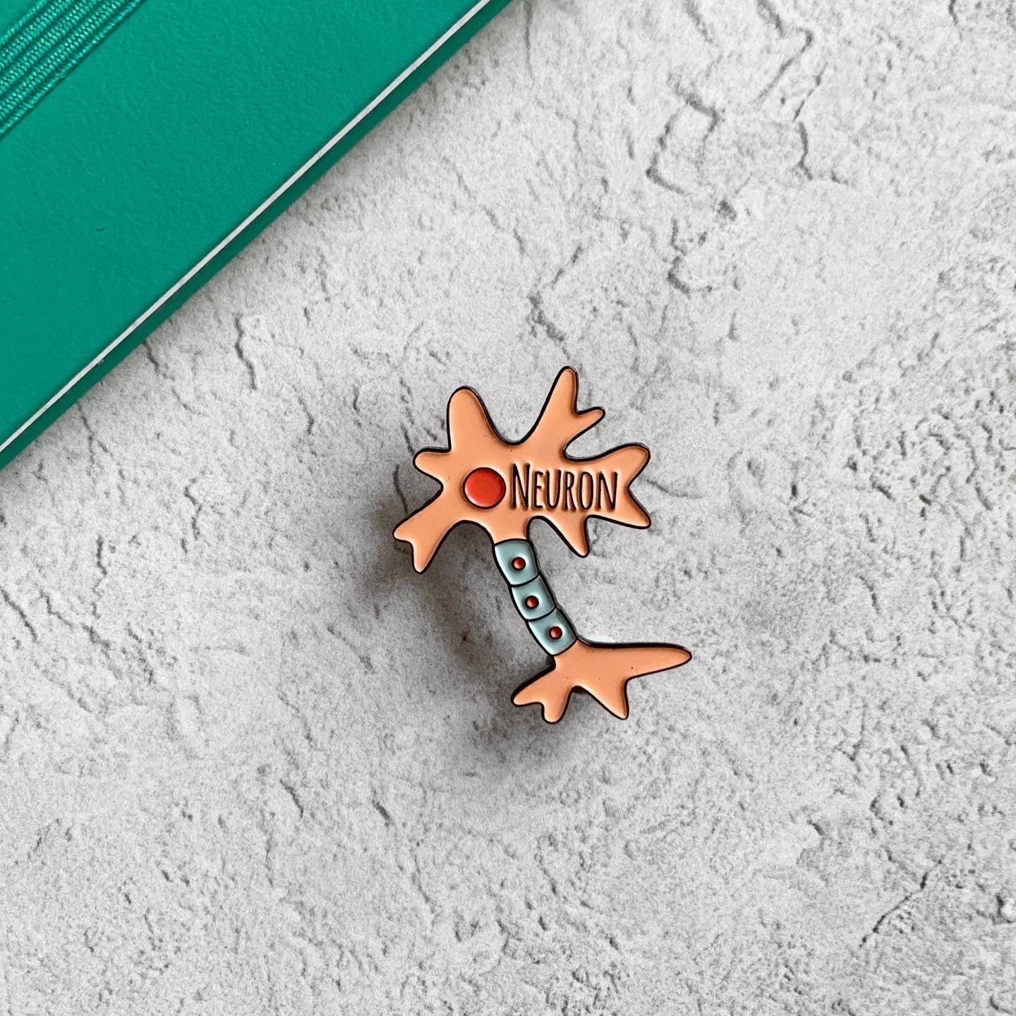 Neuron-shaped pin with 'NEURON' text on a textured white surface