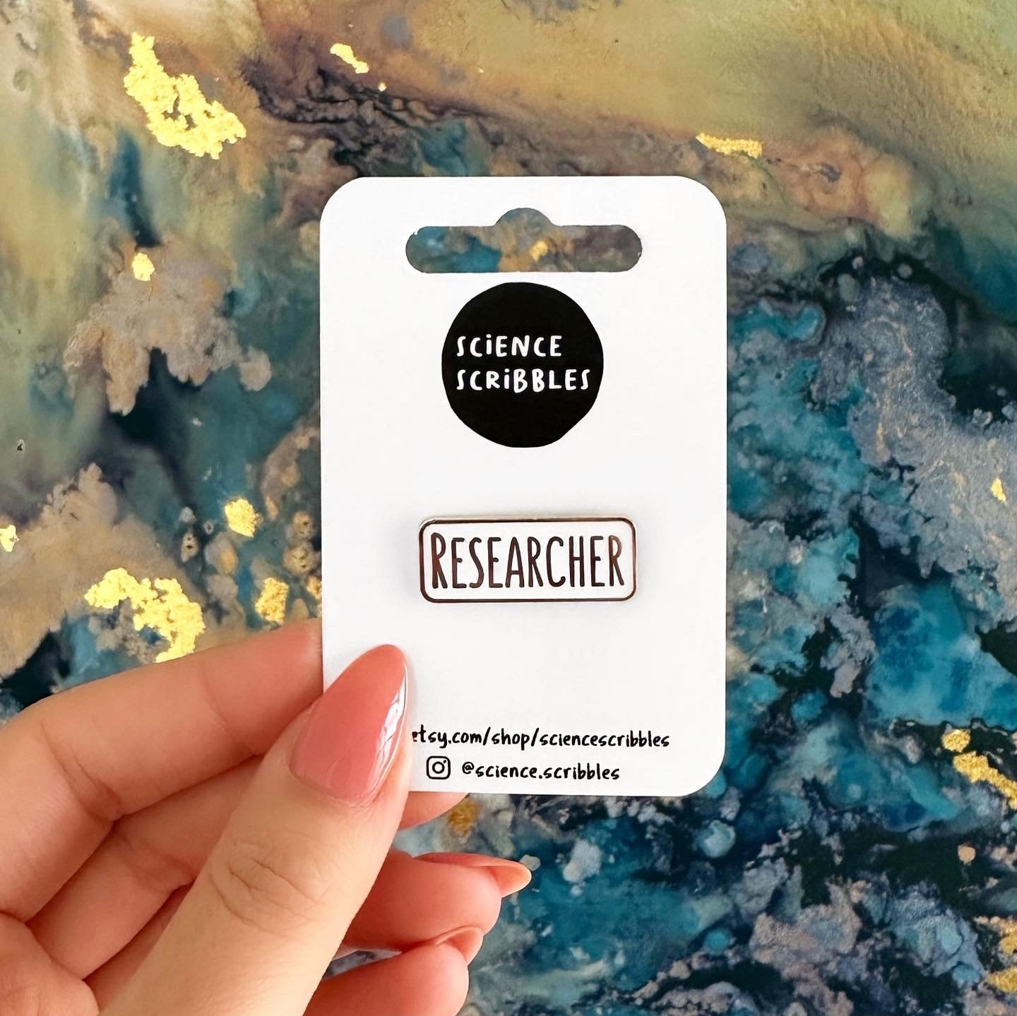 Card with 'Science Scribbles' branding held over a colorful abstract background