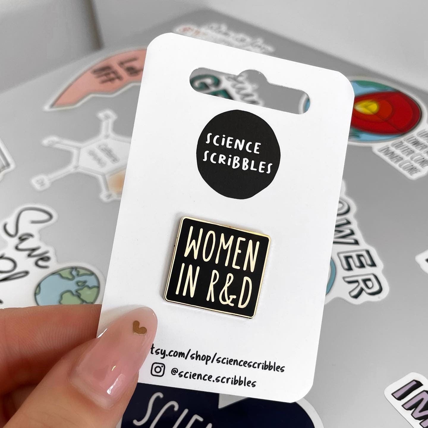 Enamel pin with 'Women in R&D' text on a Science Scribbles card