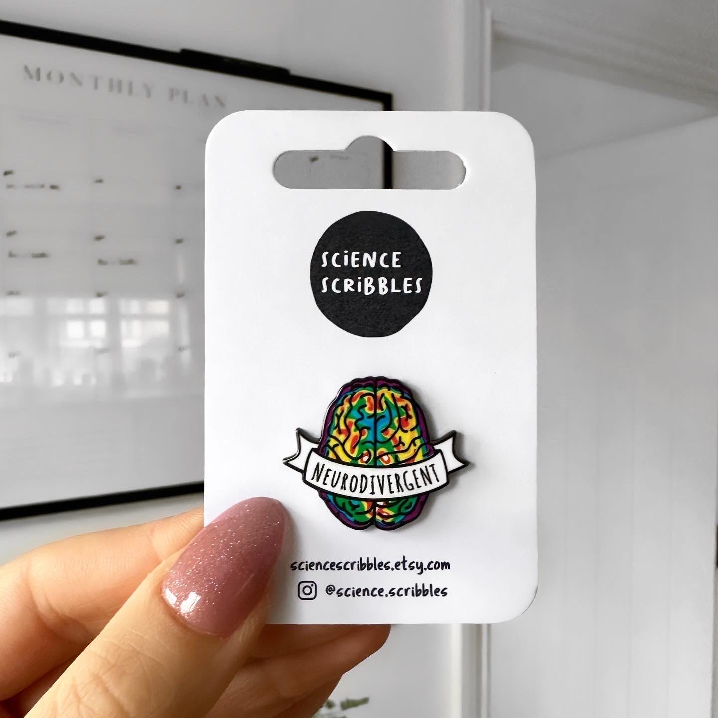 Colorful 'Neurodivergent' pin held on a card with 'Science Scribbles' branding.