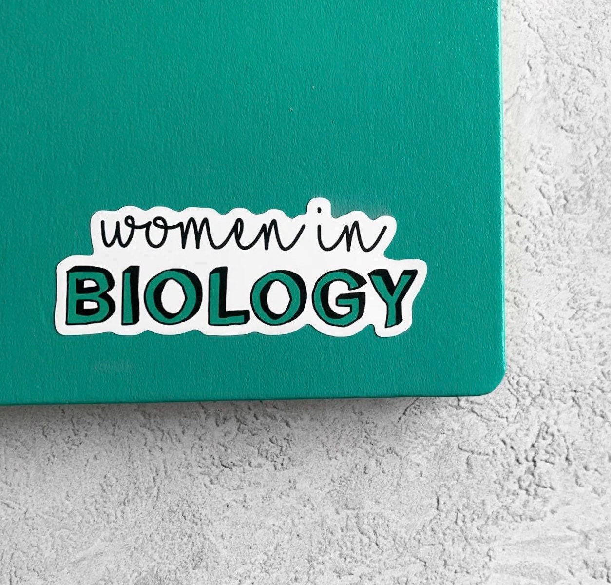 Sticker with 'women in BIOLOGY' text on a green background