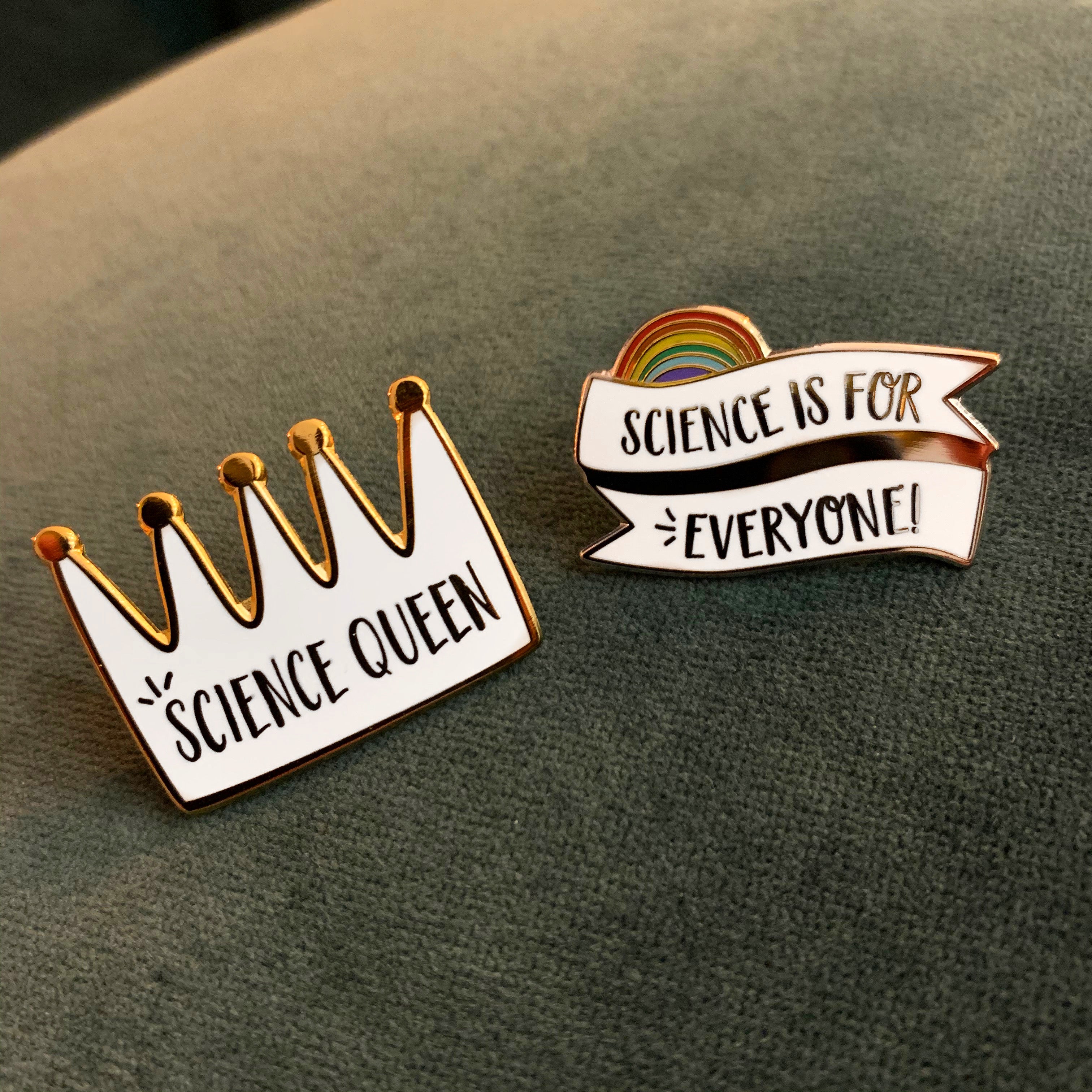 Two pins on a green background, one with 'Science Queen' and the other with 'Science is for Everyone' and a rainbow.