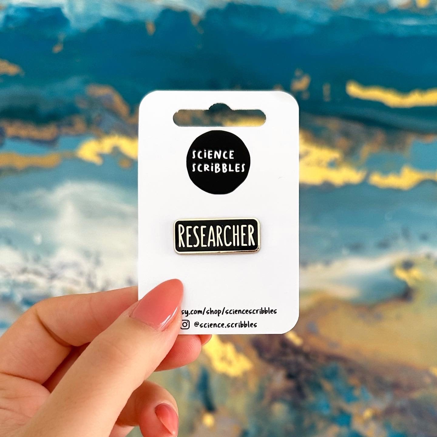 Card with 'Science Scribbles' branding held by a hand against a colorful abstract background