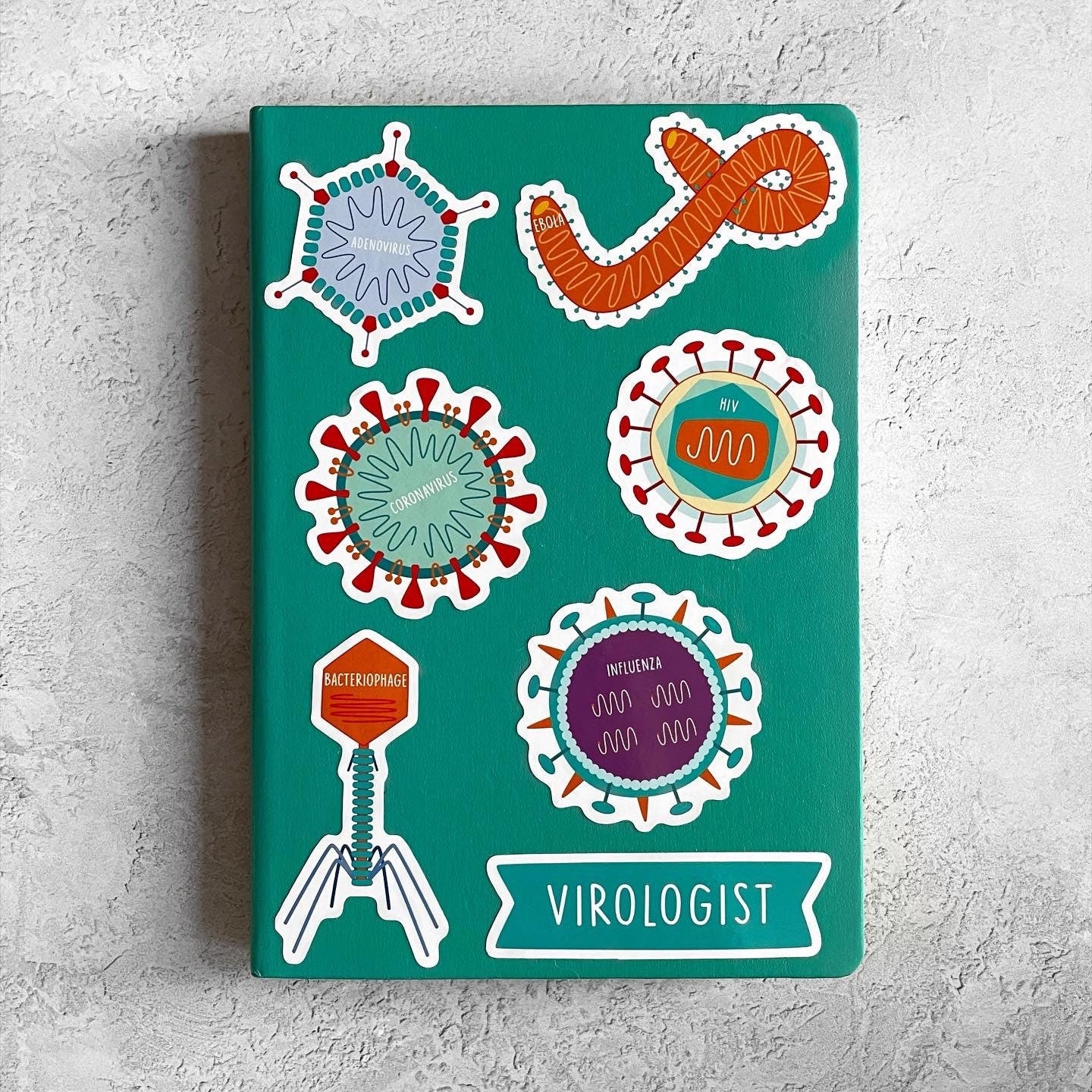 Notebook with colorful illustrations of viruses on a teal background
