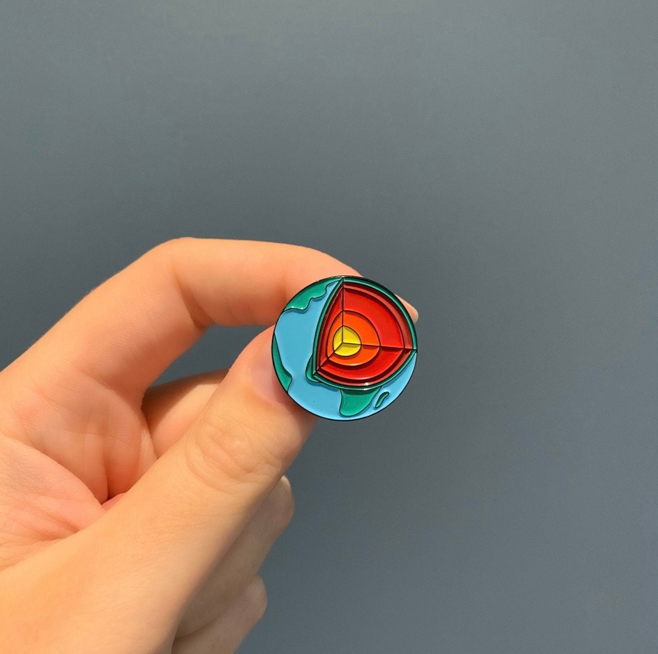 Colorful circular object held by a hand against a gray background