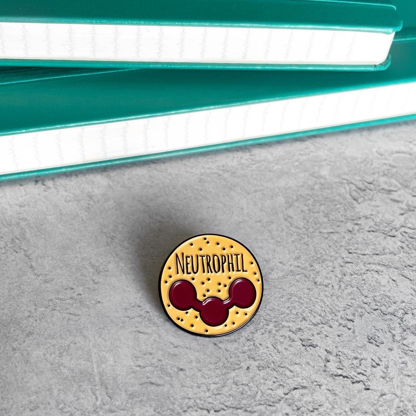 Pin with 'NEUTROPHIL' text on a textured surface
