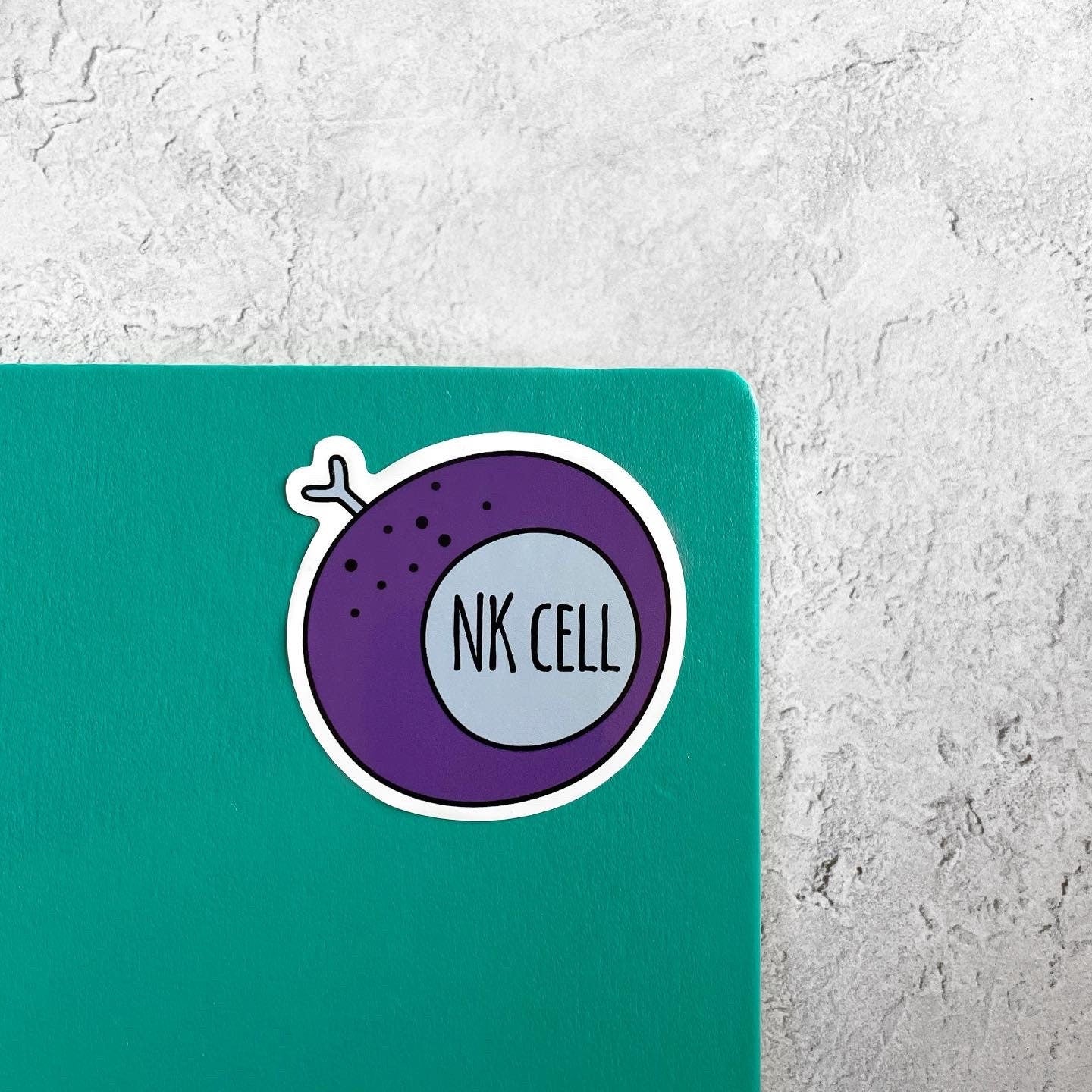 Sticker with 'NK Cell' design on a teal notebook