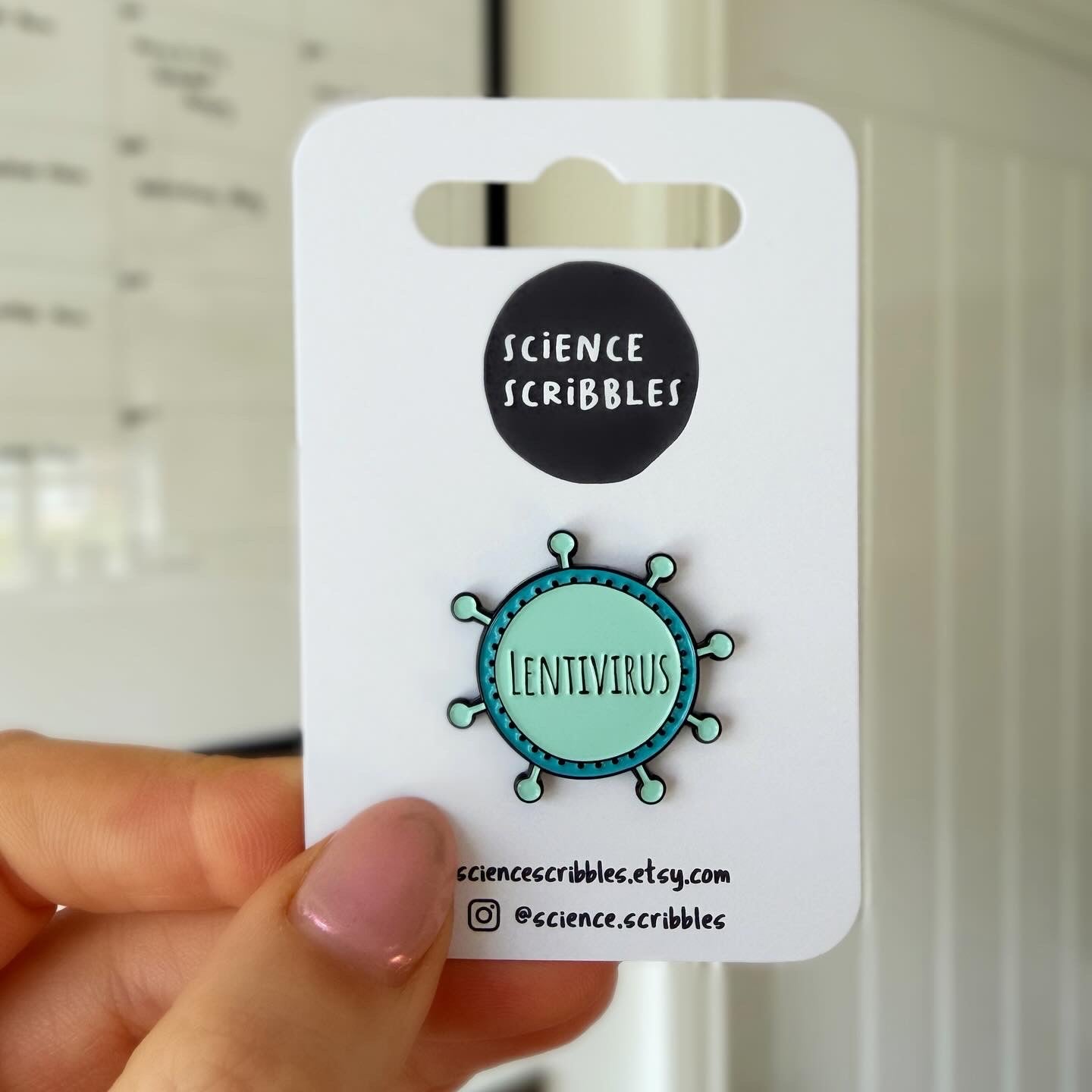 Pin with 'Lentivirus' design on a 'Science Scribbles' card held by a hand.