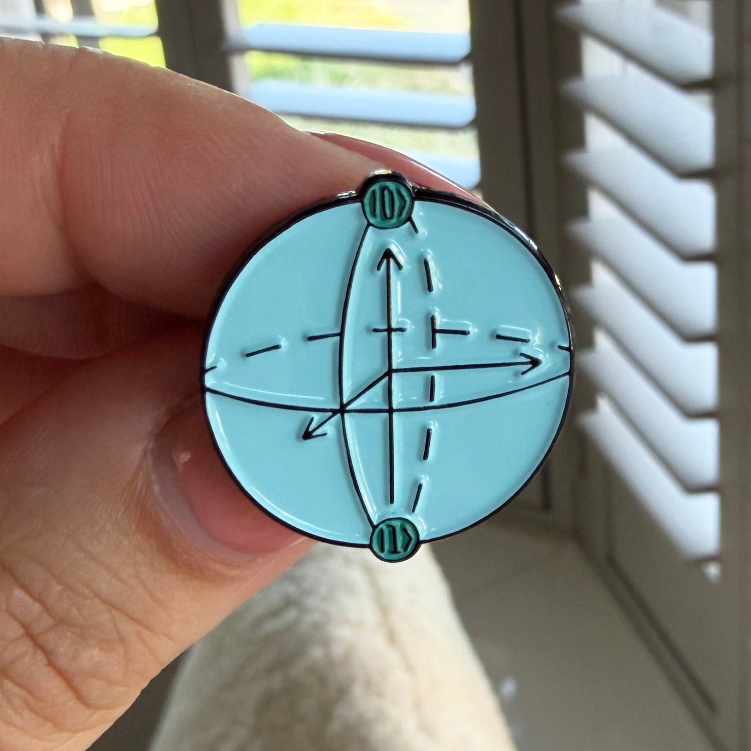 Qubit Bloch sphere blue enamel pin badge being held in a hand