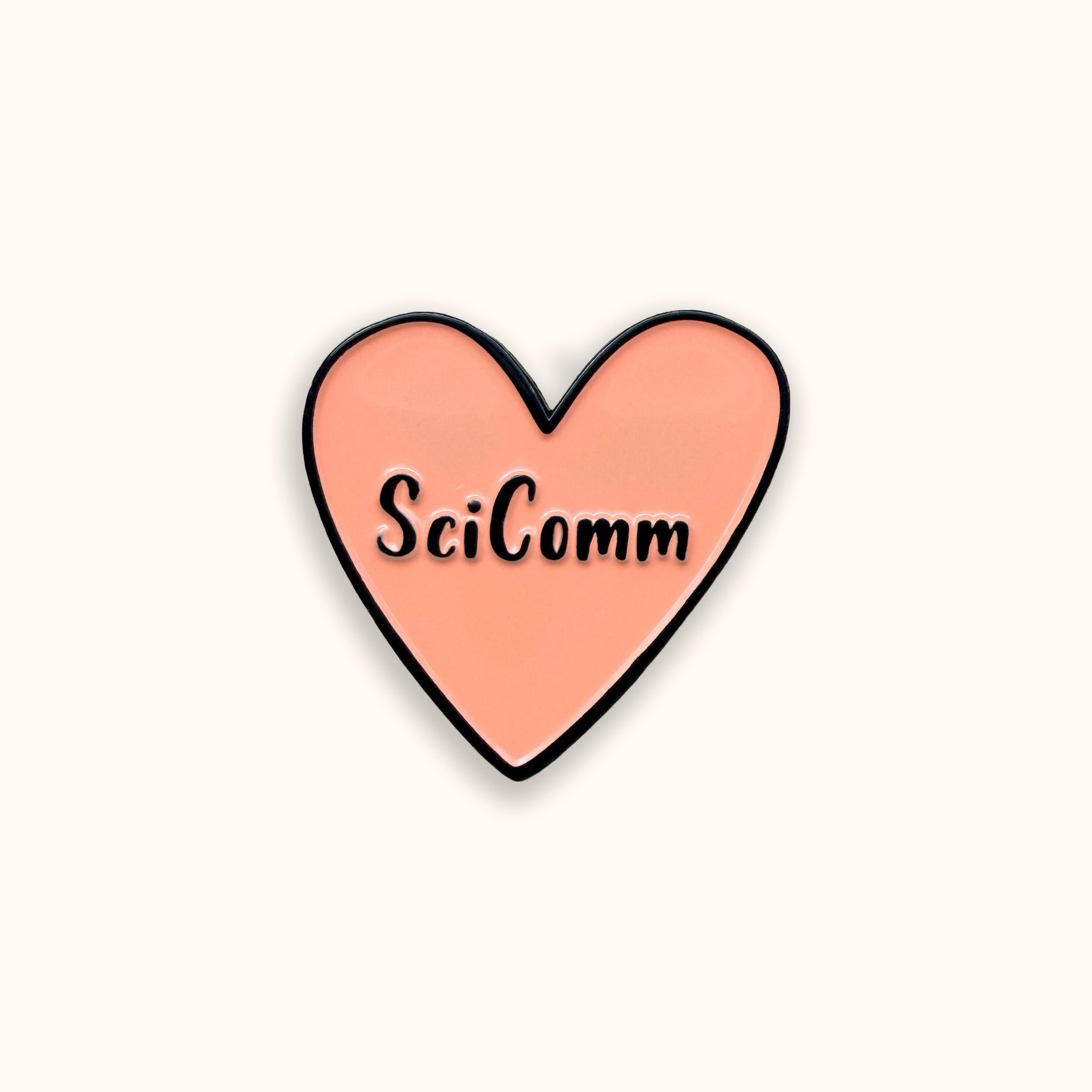 Heart-shaped pin with 'SciComm' text on a yellow background