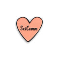 Heart-shaped pin with 'SciComm' text on a white background