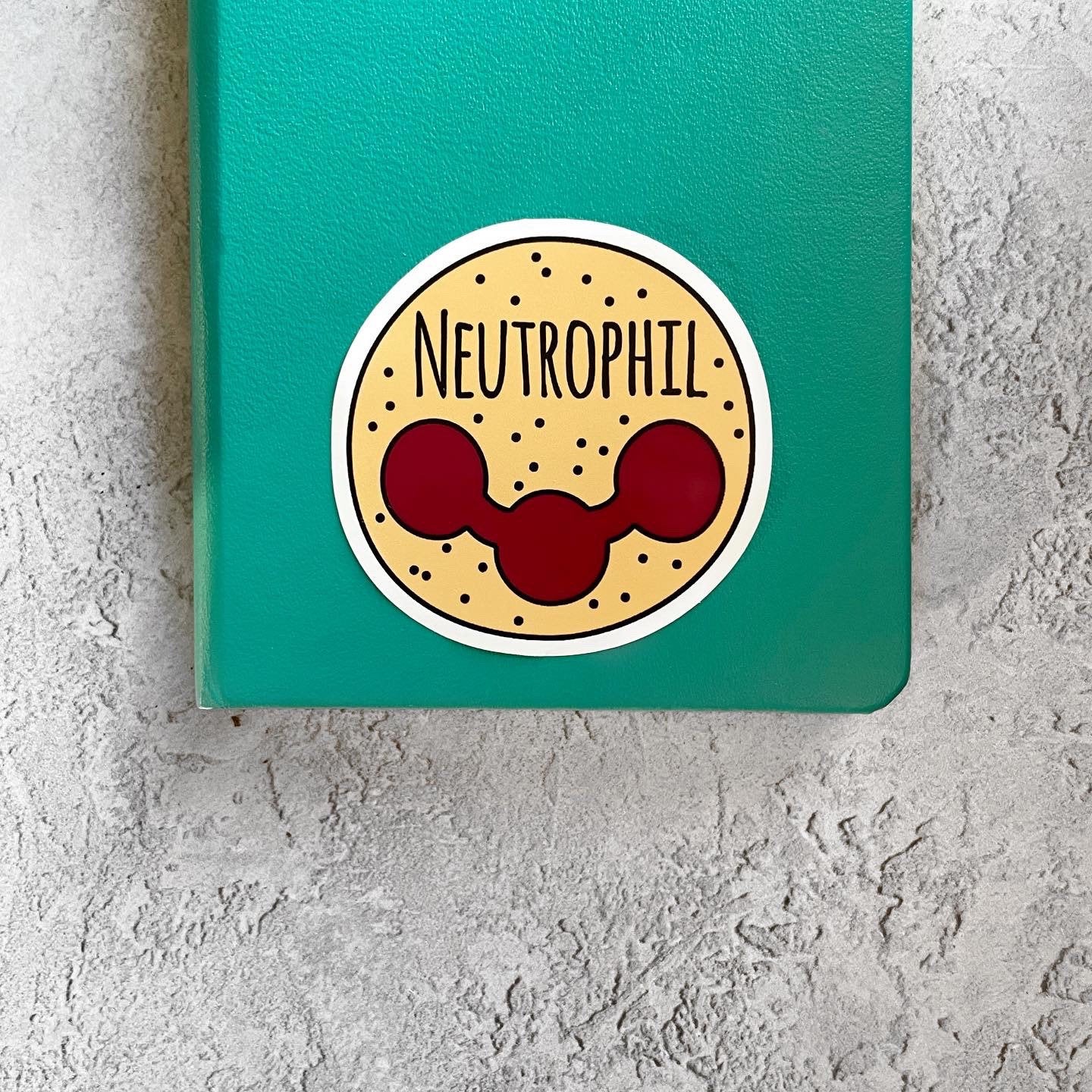 Green notebook with a sticker labeled 'Neutrophil' on a textured gray surface