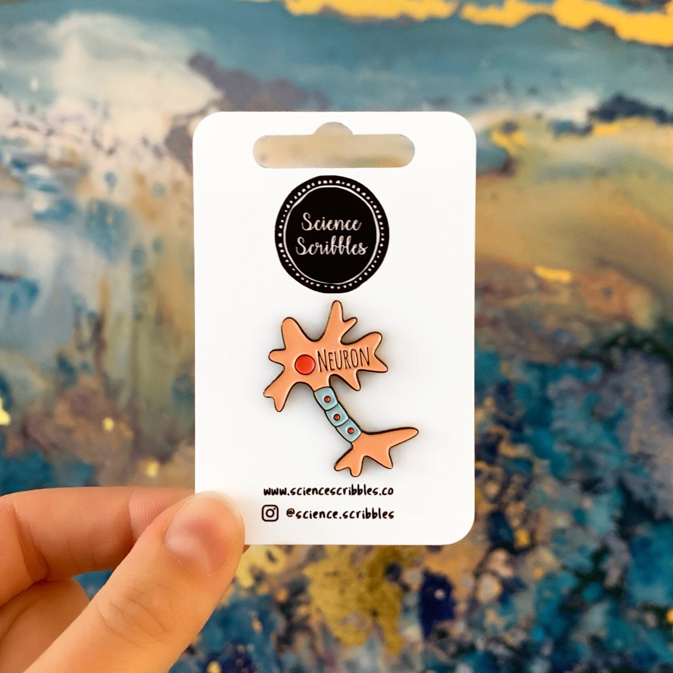 Neuron-shaped pin on a card held against a colorful abstract background