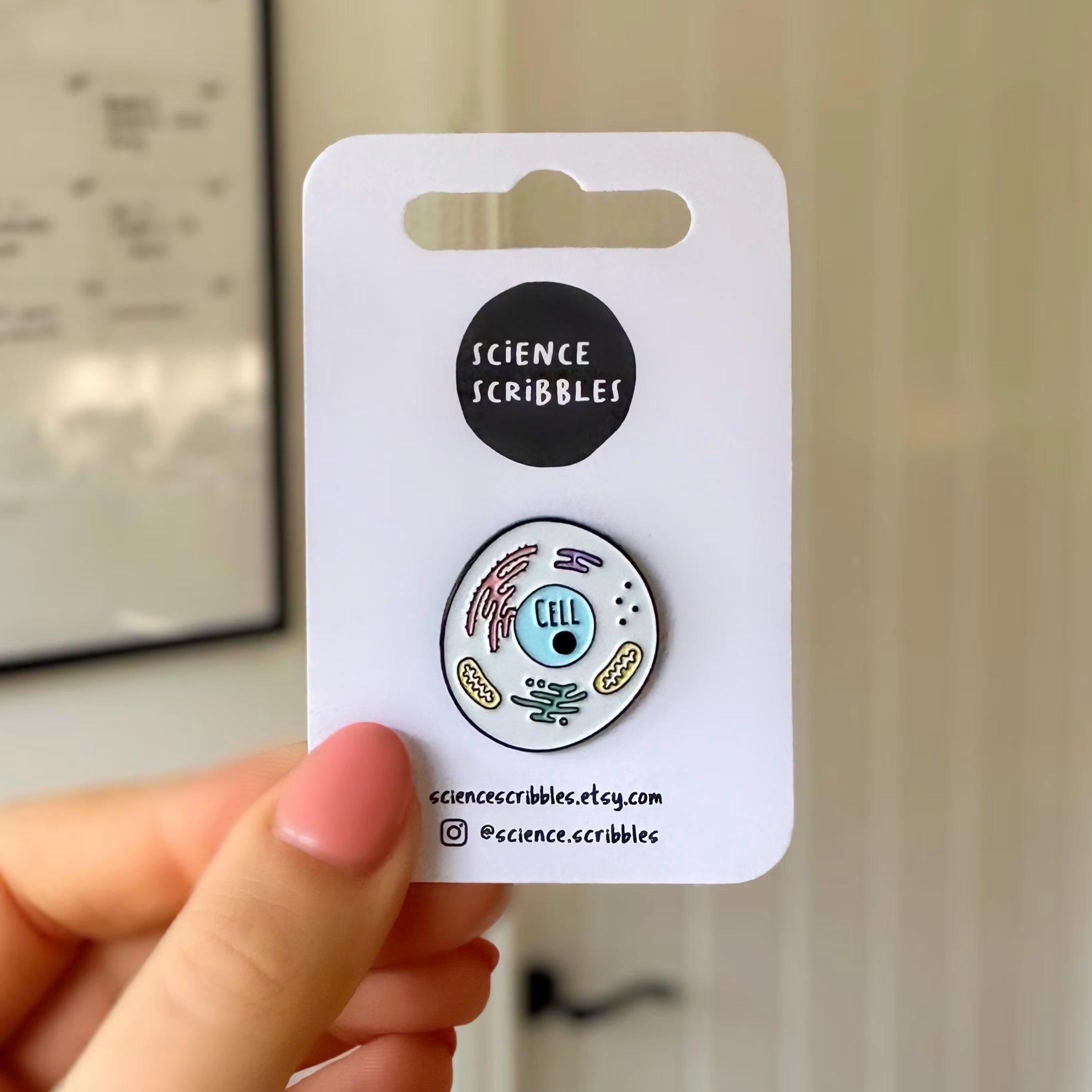 Eukaryotic cell enamel pin badge being held up by a hand