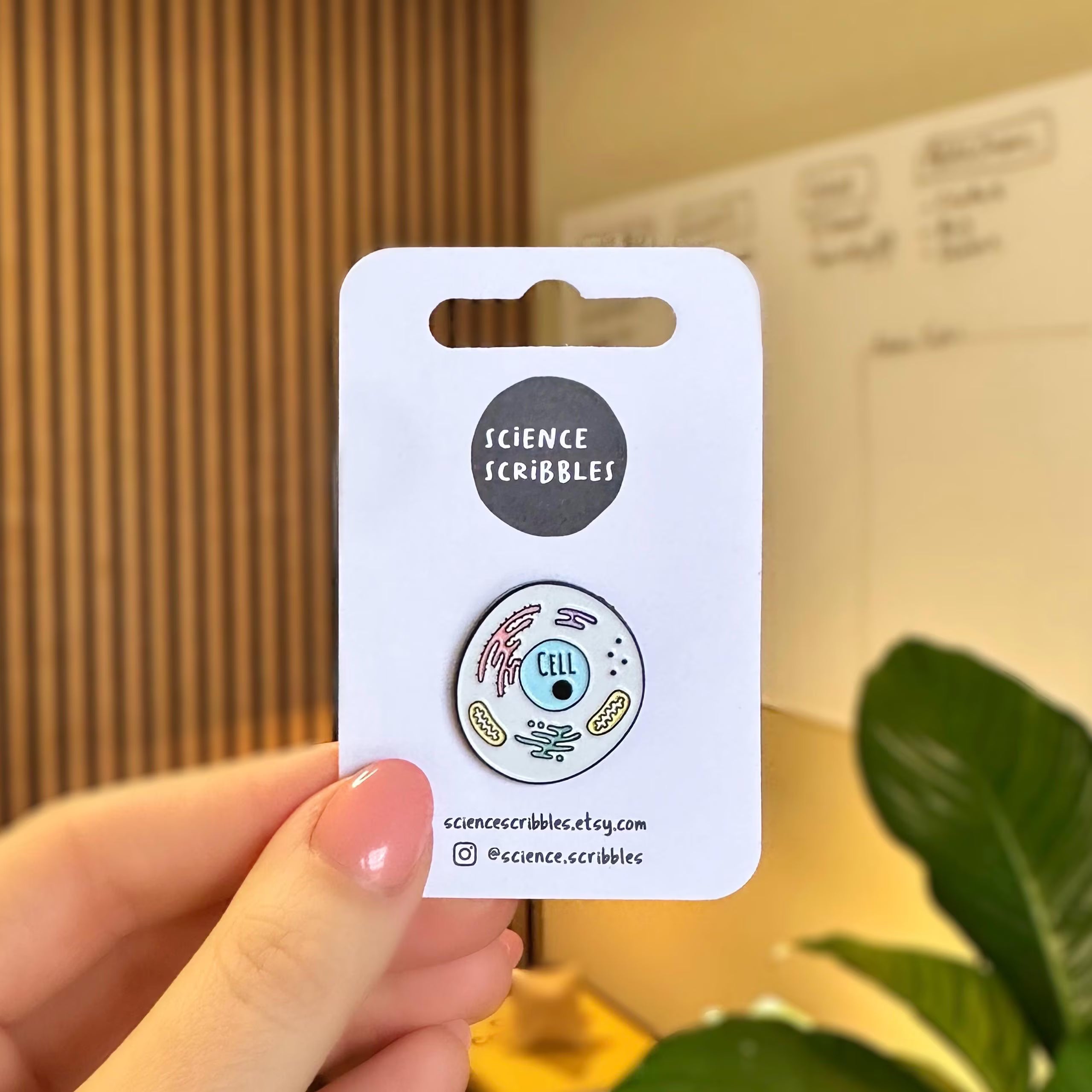 Eukaryotic cell enamel pin badge being held up by a hand