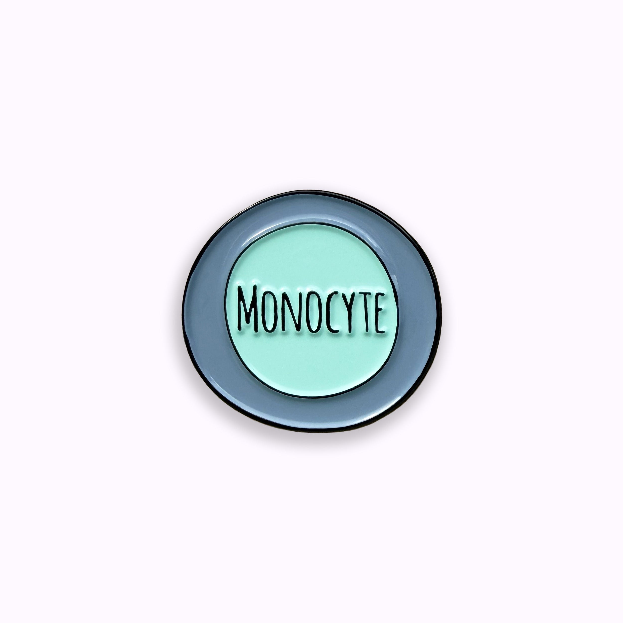 Monocyte blue and green enamel pin badge on purple background