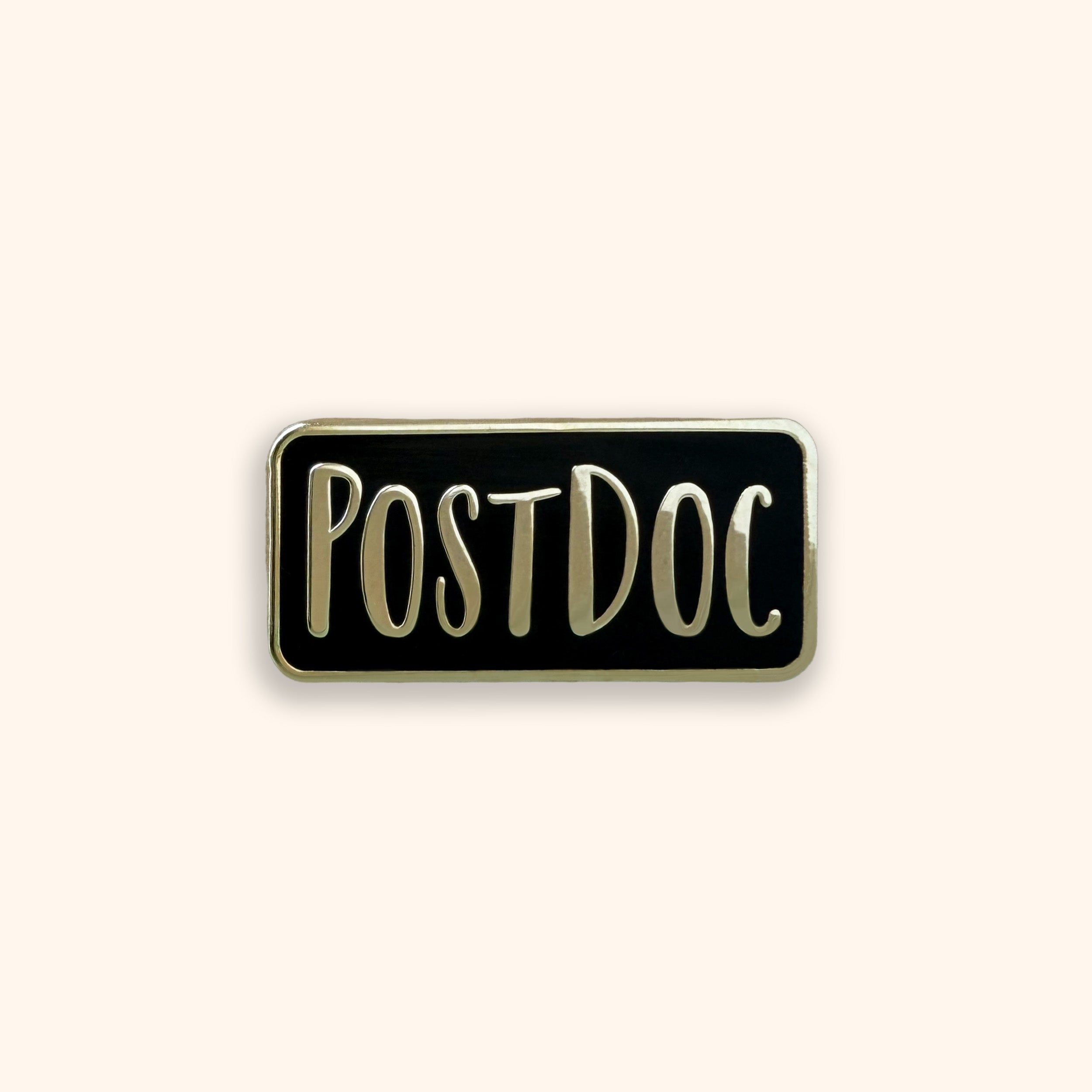 Black and gold enamel pin with the word 'POSTDOC' on it on an orange background