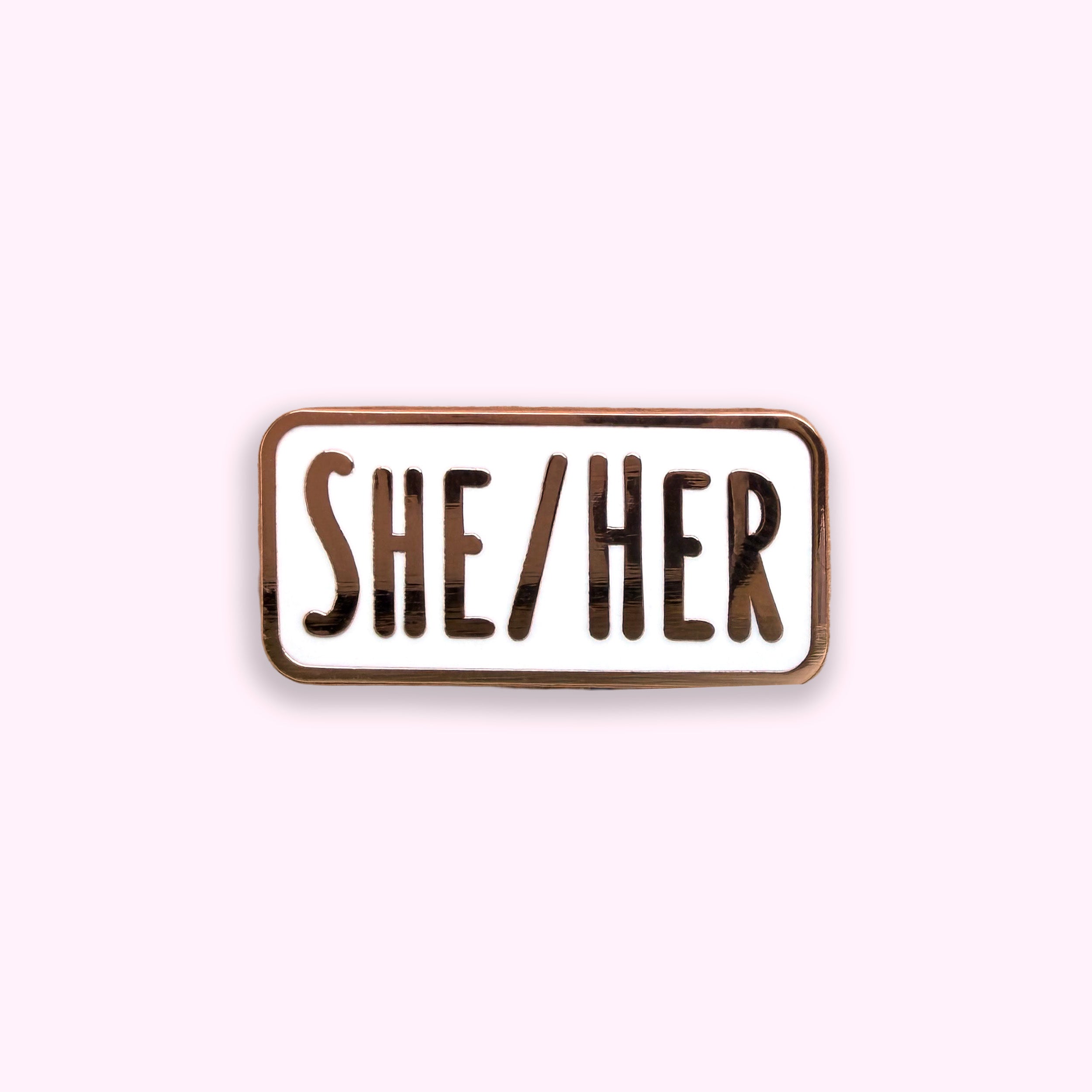 Enamel pin with 'SHE/HER' text on a white background