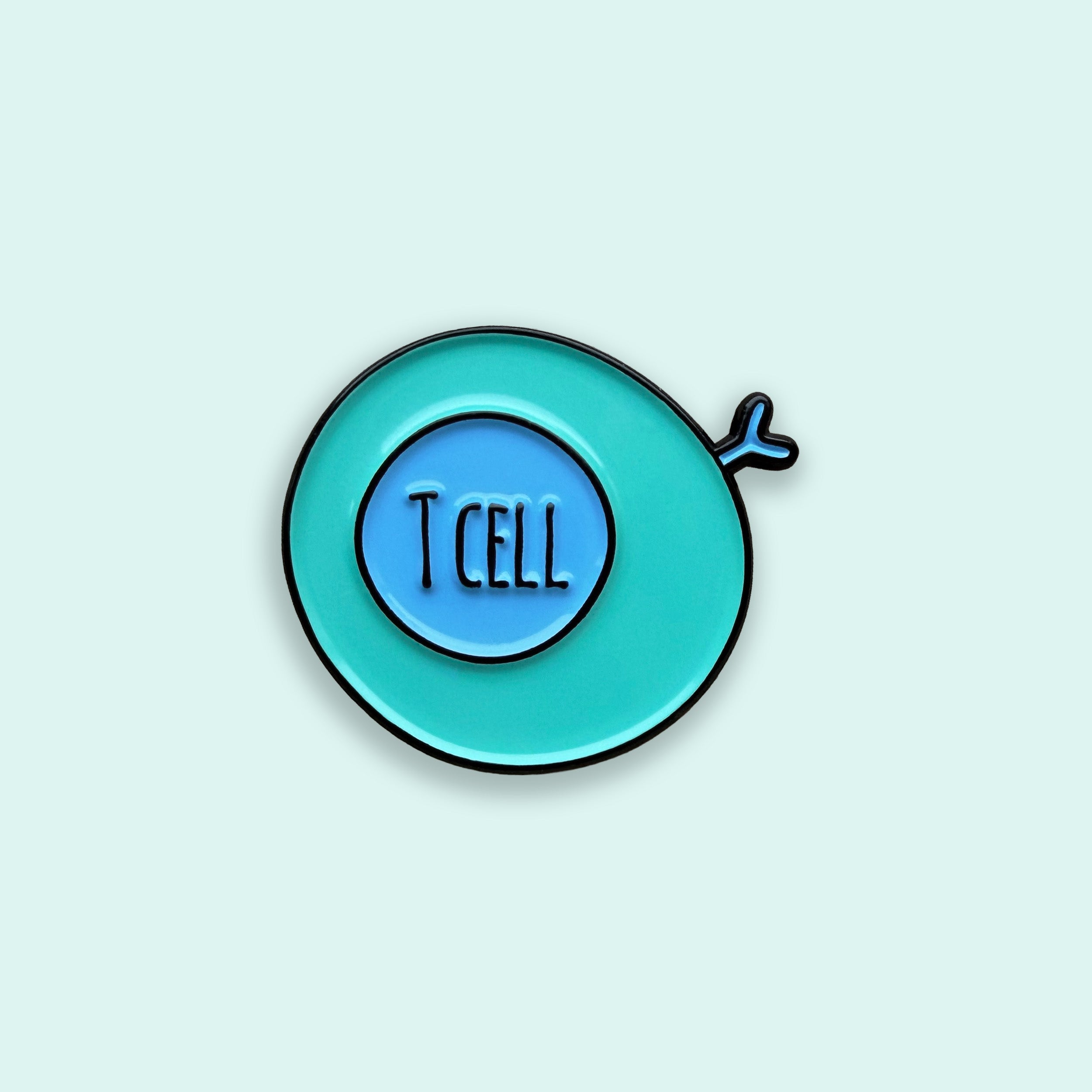 Enamel pin with 'T CELL' text on a light blue background