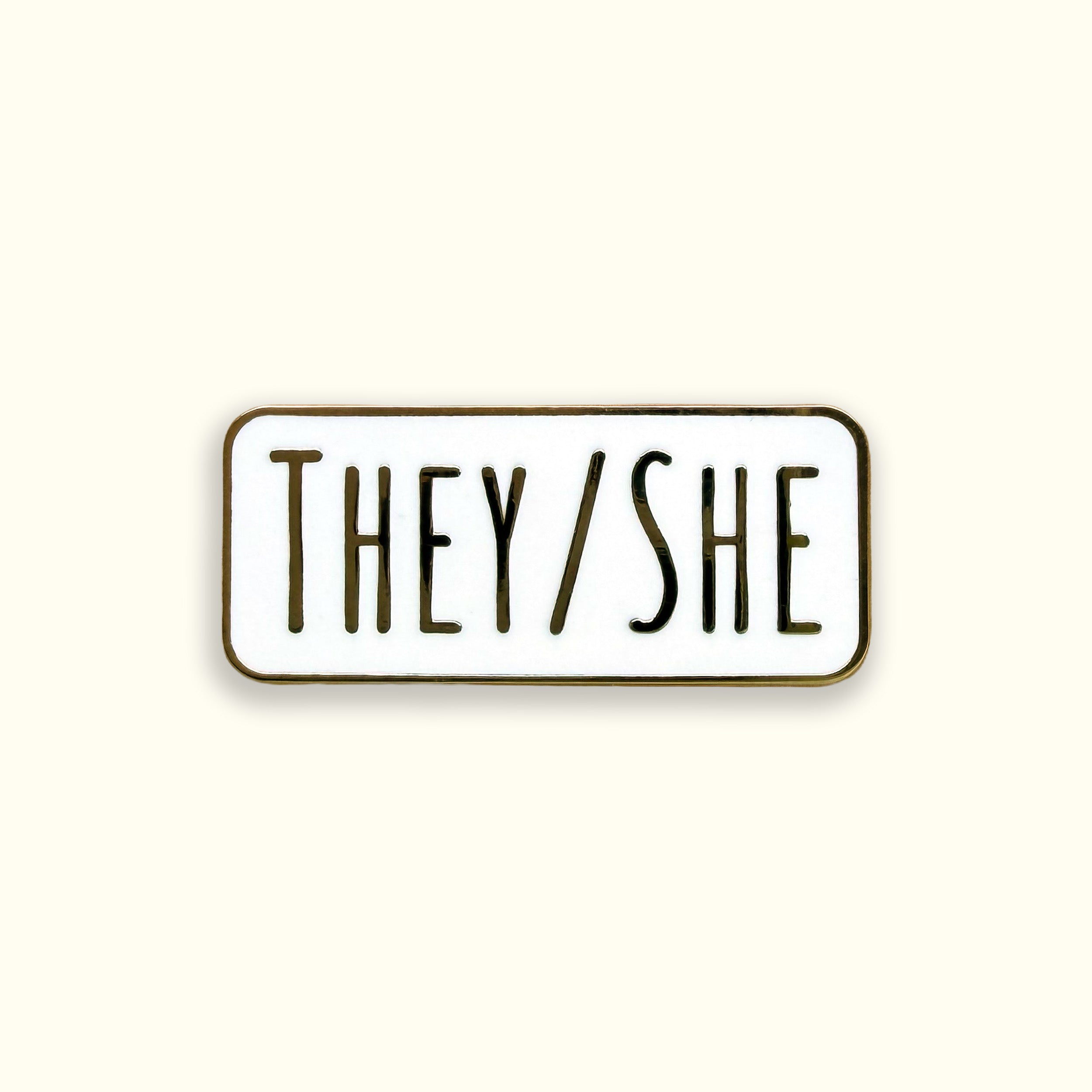 Enamel pin with 'THEY/SHE' text on a white background
