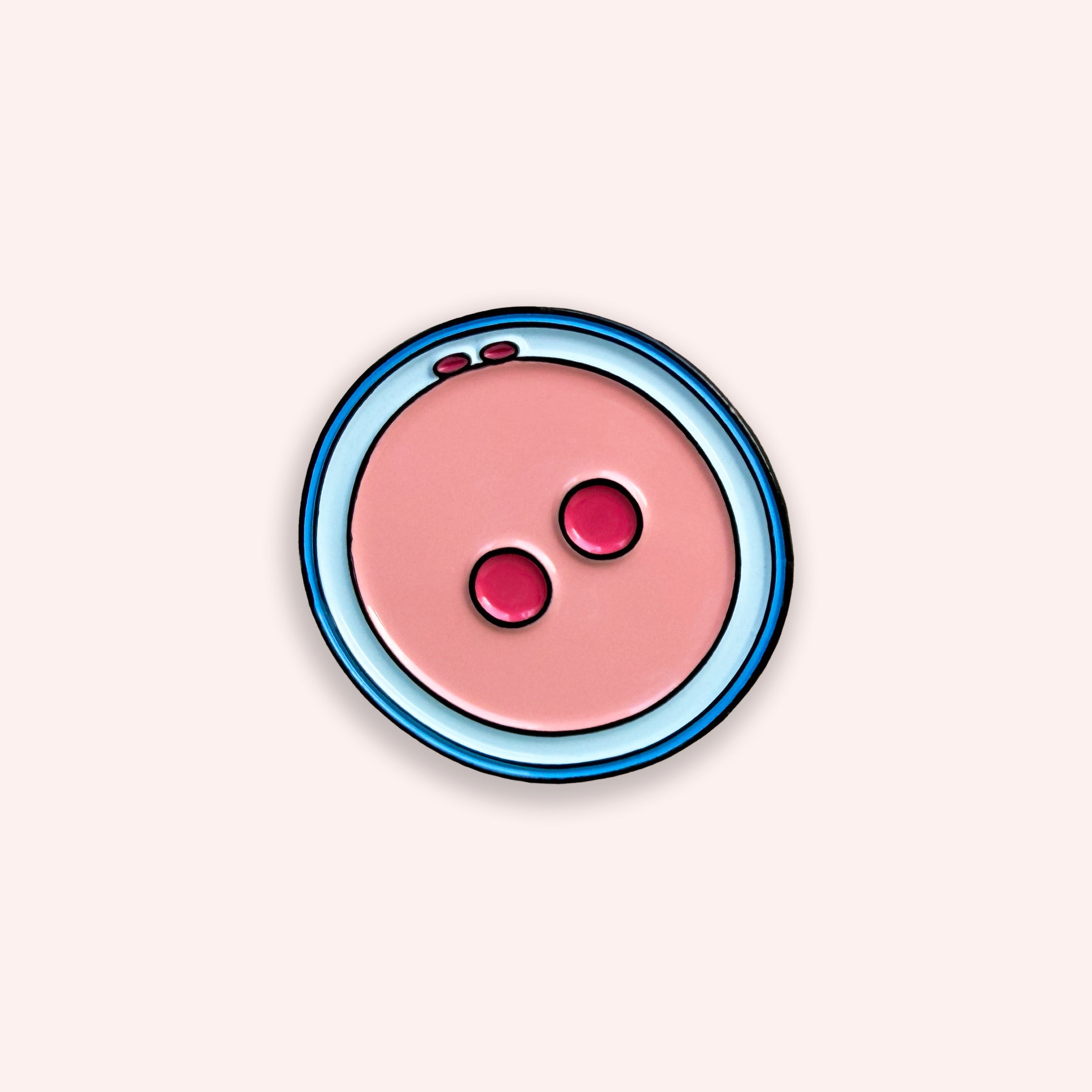 Zygote pink and blue enamel pin badge on a pink background
